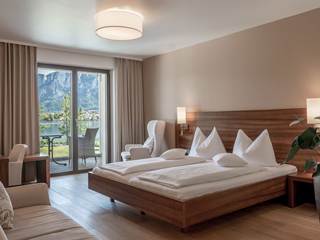 Hotelzimmer mit Pflanze in einer großen Vase, Doppelbett, Sofa, Sessel, Schreibtisch und Balkon